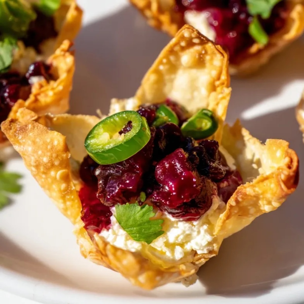 A bite-sized cranberry jalapeño dip wonton cup showing layers of sweet and spicy flavors.