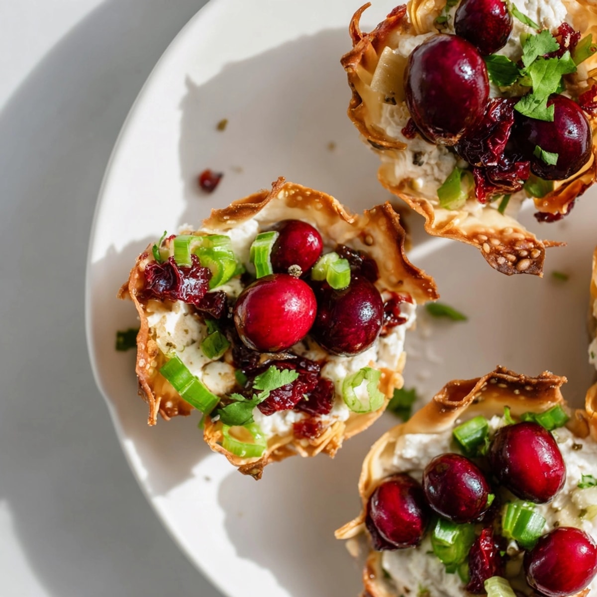 Crispy baked wonton cups overflowing with homemade cranberry jalapeño dip ready to serve.