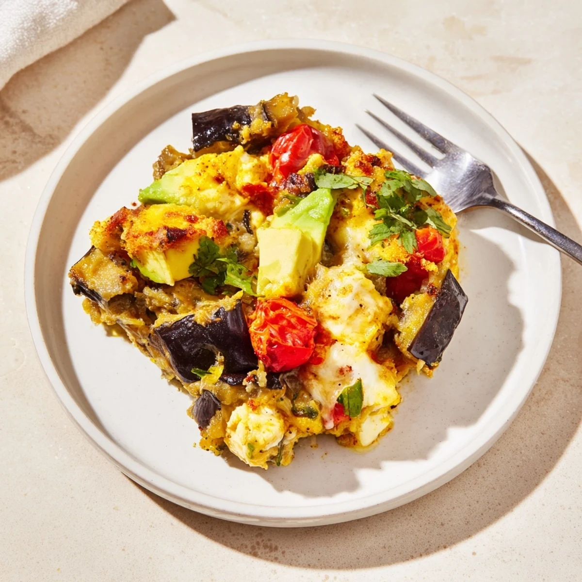 Creamy Avocado Eggplant Curry Bake topped with melted cheese and fresh cilantro sprigs.