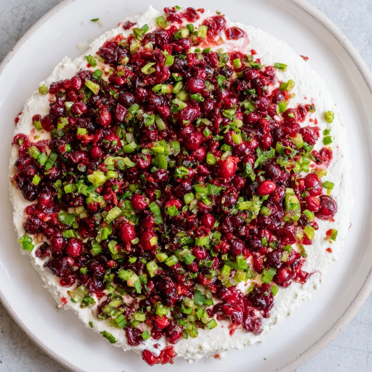 Bright red Spiced Cranberry Jalapeño Cream Cheese Dip, ready to be scooped with crackers.