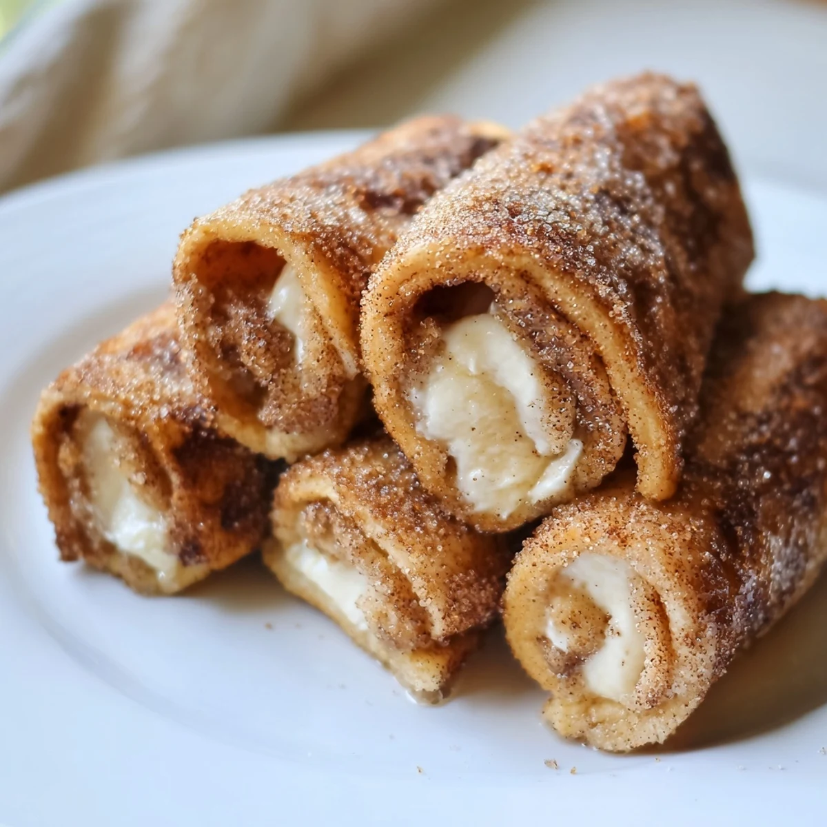 Warm Easy French Toast Roll-Ups show a soft, cream cheese filling peeking out, ideal for a tasty snack.