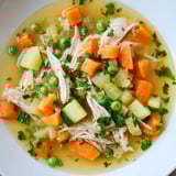 Homemade Spring Garden Chicken Soup, featuring shredded chicken with fresh parsley for serving.