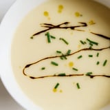 Velvety Celery Root Bisque in a rustic white bowl, topped with microgreens and a swirl of cream.  
