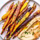 Colorful rainbow carrots and hummus appetizer garnished with fresh parsley.  