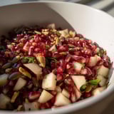 Overhead view of Pomegranate and Walnut Salad, showcasing jewel-like pomegranate seeds, crisp pear slices, and crunchy pumpkin seeds tossed with fresh mint.
