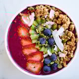 A vibrant bowl of Beet and Berry Smoothie Bowl garnished with fresh mint, coconut, and berries, ready for a quick snack.