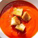 Warm roasted tomato soup with crunchy croutons, perfect for a cozy vegetarian dinner.  