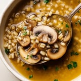 Hearty Mushroom and Barley Soup served in a ceramic mug, garnished with fresh parsley and a lemon wedge.