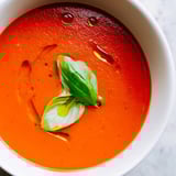 Creamy, velvety Tomato and Basil Soup simmered with onions and garlic, featuring ripe tomatoes and aromatic basil for a comforting Italian-inspired meal.