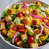 A bowl of salad with tomatoes, lettuce, and cheese.