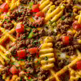 A plate of nachos de gaufrettes de pommes de terre aux tacos.