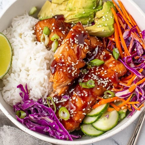 Glazed soy-maple salmon rice bowls topped with fresh vegetables and avocado slices.  