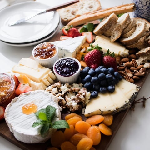 A colorful jam-infused brunch board with cheeses, fruits, and artisan breads.  