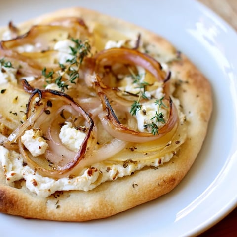 Golden caramelized onion and apple flatbread topped with creamy goat cheese and herbs.  