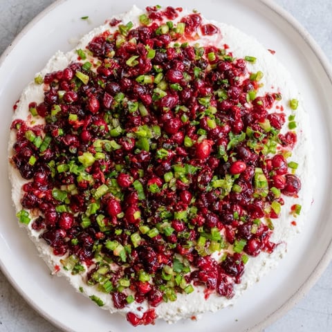 Bright red Spiced Cranberry Jalapeño Cream Cheese Dip, ready to be scooped with crackers.