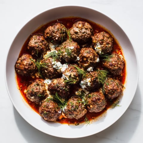 Tender Instant Pot Greek Meatballs swimming in vibrant tomato sauce, topped with creamy lemon-feta.
