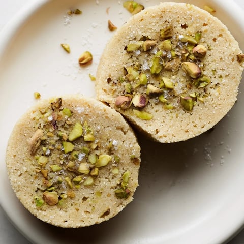Golden, buttery Salted Pistachio Slice & Bake Shortbread cookies glistening with flaky sea salt, ready to enjoy.