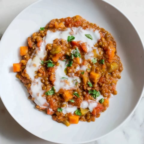 Steaming Creamy Tomato Basil Lentil Bolognese, glistening with fresh basil, ready for a comforting dinner.
