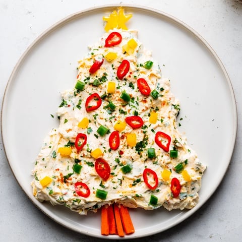Vibrant Chili Pepper Christmas Tree Dip, a spicy appetizer arranged with colorful vegetables and herbs.