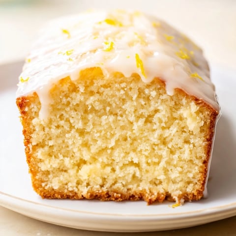 A close-up of a golden Lemon Yogurt Cake, drizzled with sweet lemon glaze, ready to enjoy.