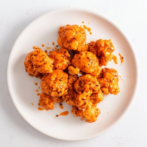 Golden, crispy Buffalo Cauliflower Bites, coated in spicy sauce, ready to be served with cooling ranch.