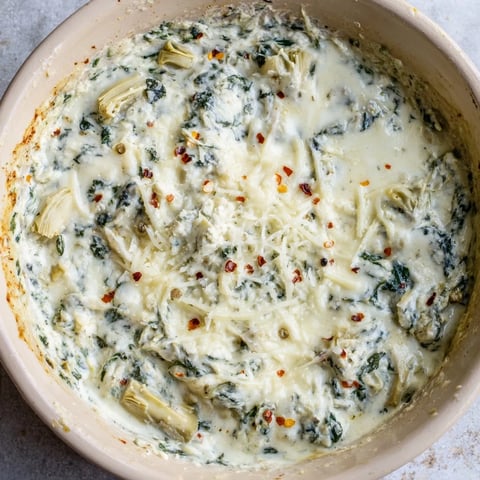 Spinach Artichoke Dip, bubbly and golden, served with crispy tortilla chips for dipping.