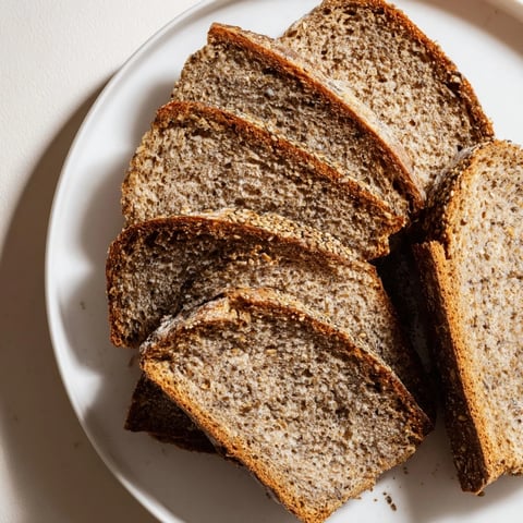 A rustic loaf of Latvian Rupjmaize bread, boasting a dark crust and caraway seeds atop.