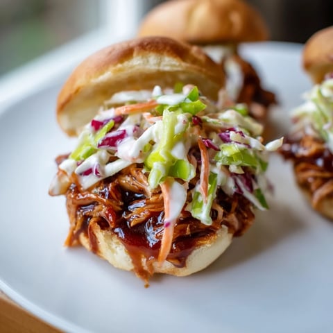 Golden-brown BBQ Chicken Sliders, bursting with juicy pulled chicken and creamy, cool slaw.