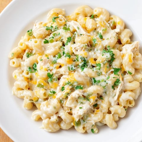 Creamy Green Chili Chicken Mac, topped with melted cheese and fresh cilantro, looks delicious.