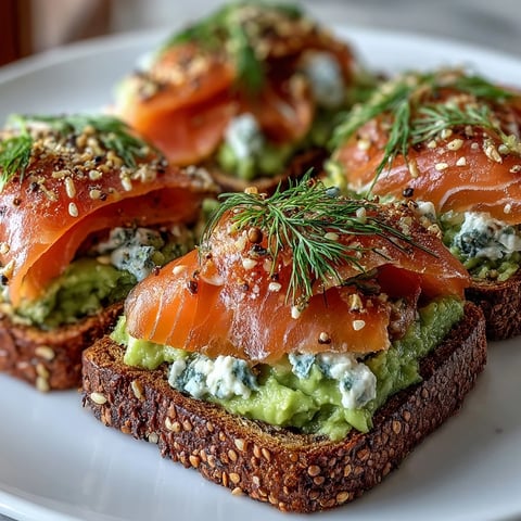 Golden-brown keto avocado bread toasts with smoked salmon and everything seasoning garnish, displayed on a rustic white platter.