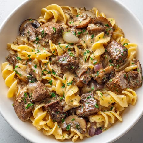A bowl of pasta with meat and mushrooms.