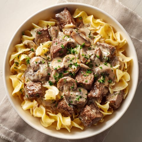 A bowl of pasta with meat and mushrooms.