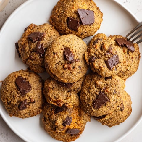 Enjoy freshly baked pumpkin chocolate chip cookies served with a glass of cold milk.  