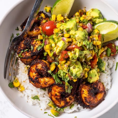 Flavorful blackened shrimp nestled on fluffy rice with creamy avocado corn salsa.  