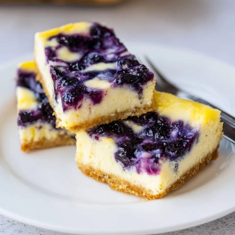 Vibrant blueberry lemon cheesecake bars with a smooth texture, great for summer gatherings.  