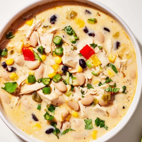 Creamy Slow Cooker White Chicken Chili with black beans, garnished with cheese, perfect for a cozy dinner.