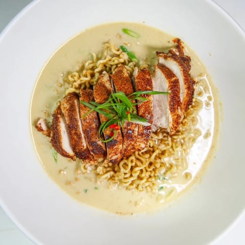 Enjoy a close-up of this Fiery Chicken Ramen, capturing the vibrant colors and rich aromas of the flavorful, spicy dish.