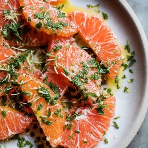 A beautiful bowl of winter fruit salad: juicy clementines and fresh mint, ready to serve.