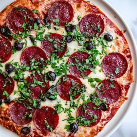 Vibrant arrangement of pepperoni slices topped with halved black olives, a quick and easy appetizer.