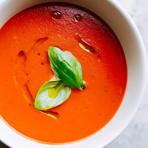 Creamy, velvety Tomato and Basil Soup simmered with onions and garlic, featuring ripe tomatoes and aromatic basil for a comforting Italian-inspired meal.
