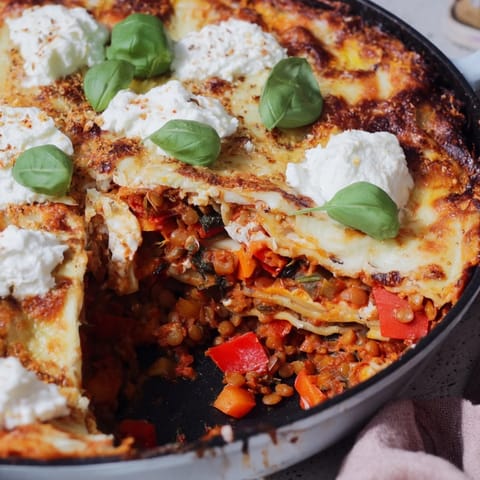 A close-up of hearty One-Pan Smoky Veggie Lentil Lasagne with red lentils and melted mozzarella.  