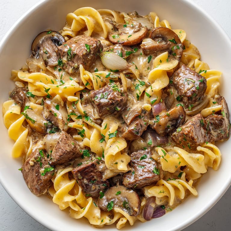 A bowl of pasta with meat and mushrooms.