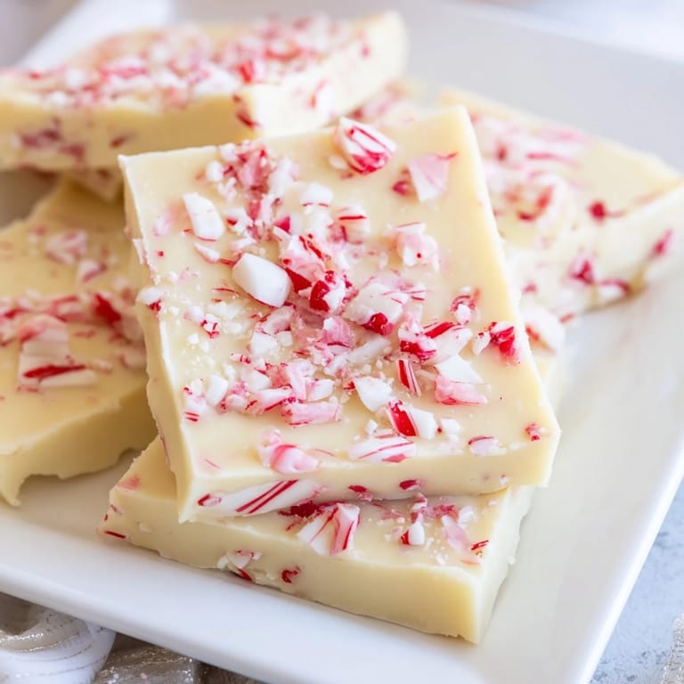Shiny, creamy, and festive White Chocolate Peppermint Bark Fudge, a perfect holiday dessert square.