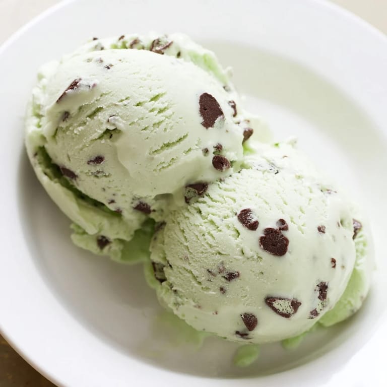Creamy mint chocolate chip ice cream, speckled with mini chocolate chips, ready to enjoy on a cone.